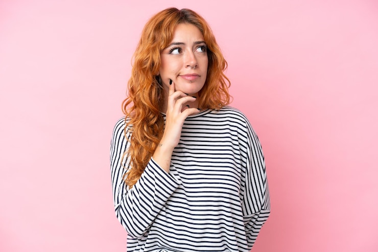 Foto jovem mulher caucasiana isolada em fundo rosa com dúvidas e pensando