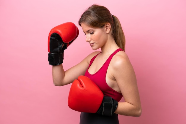 Jovem mulher caucasiana isolada em fundo rosa com luvas de boxe