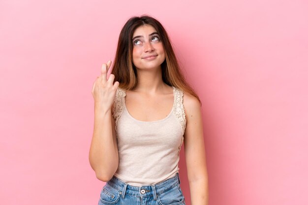 Foto jovem mulher caucasiana isolada em fundo rosa com os dedos cruzando e desejando o melhor