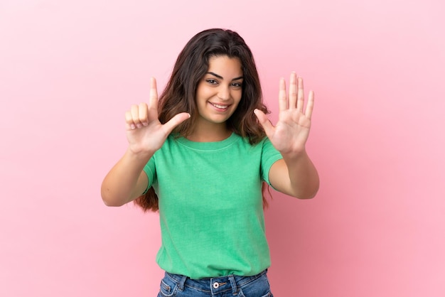 Jovem mulher caucasiana isolada em fundo rosa contando sete com os dedos