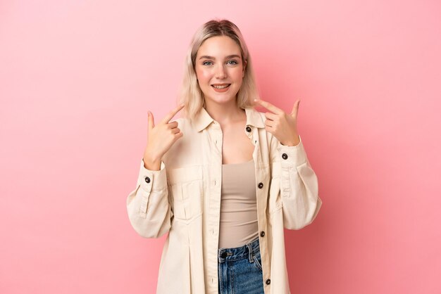 Jovem mulher caucasiana isolada em fundo rosa, dando um polegar para cima gesto