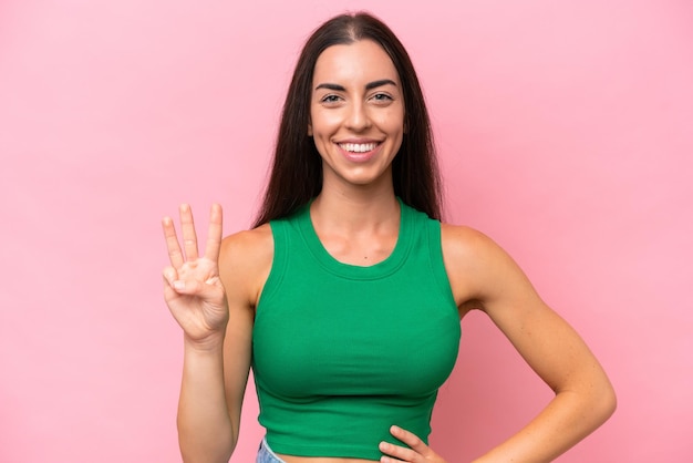 Jovem mulher caucasiana isolada em fundo rosa feliz e contando três com os dedos