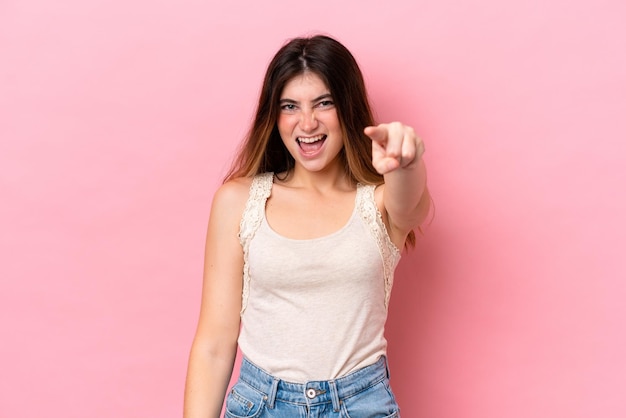 Jovem mulher caucasiana isolada em fundo rosa frustrada e apontando para a frente