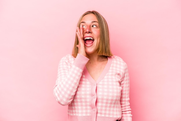 Jovem mulher caucasiana isolada em fundo rosa gritando animada para a frente