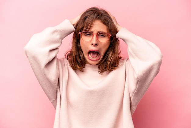 Jovem mulher caucasiana isolada em fundo rosa gritando muito animada apaixonada satisfeita com algo