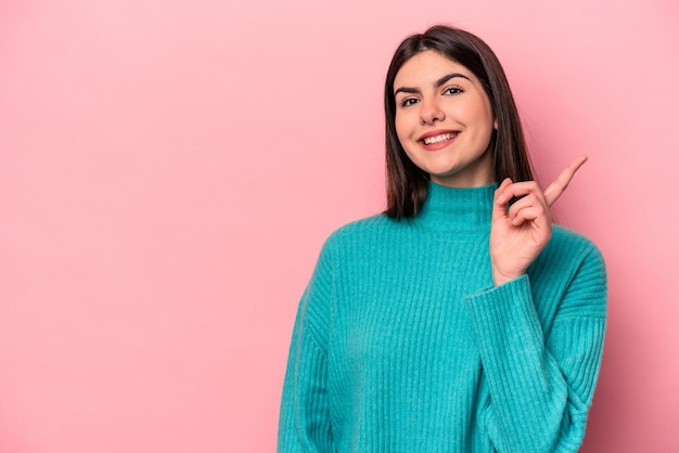 Jovem mulher caucasiana isolada em fundo rosa, mostrando o número um com o dedo