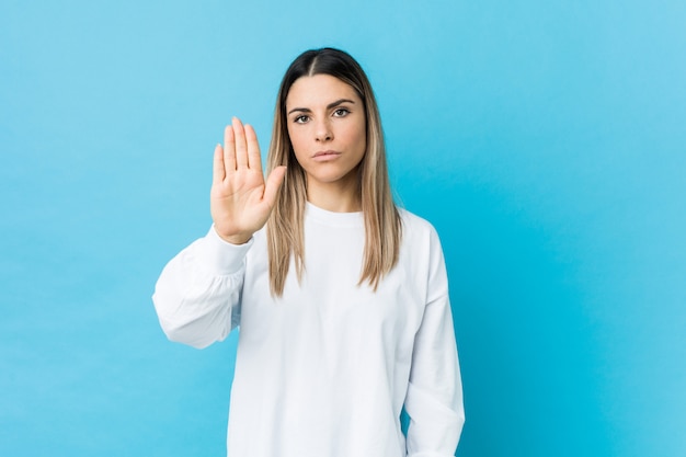 Jovem mulher caucasiana isolada em pé com a mão estendida, mostrando o sinal de stop, impedindo-o.