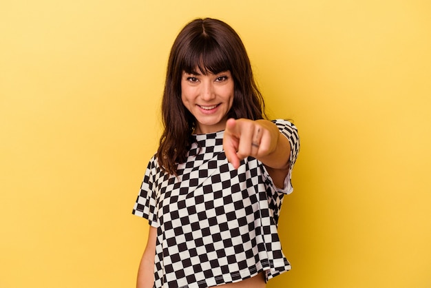 Jovem mulher caucasiana isolada em sorrisos alegres de fundo amarelo, apontando para a frente.