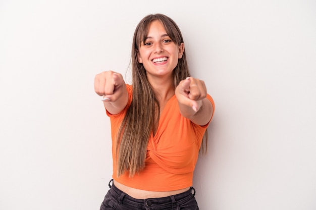 Jovem mulher caucasiana isolada em sorrisos alegres de fundo branco, apontando para a frente.