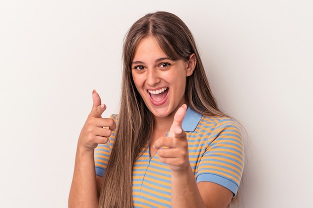 Jovem mulher caucasiana isolada em sorrisos alegres de fundo branco, apontando para a frente.