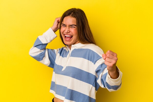 Jovem mulher caucasiana isolada em um fundo amarelo, dançando e se divertindo.