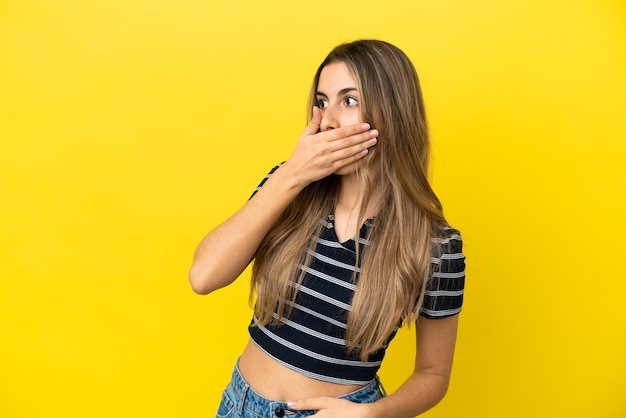 Foto jovem mulher caucasiana isolada em um fundo amarelo fazendo gesto de surpresa enquanto olha para o lado