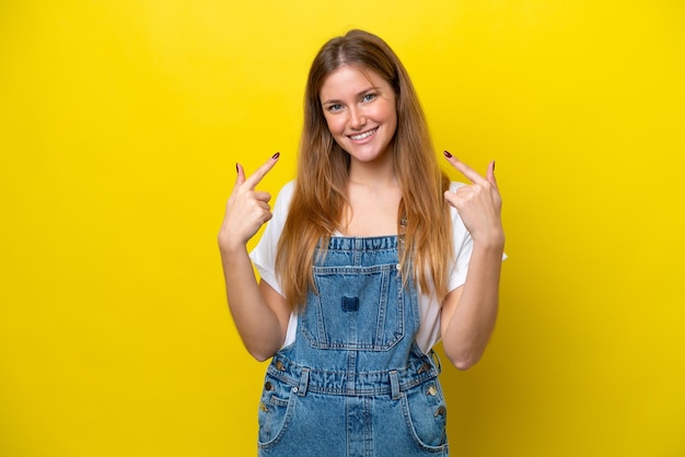 Jovem mulher caucasiana isolada em um fundo amarelo fazendo um gesto de polegar para cima