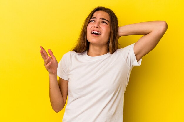 Jovem mulher caucasiana isolada em um fundo amarelo, gritando de raiva.