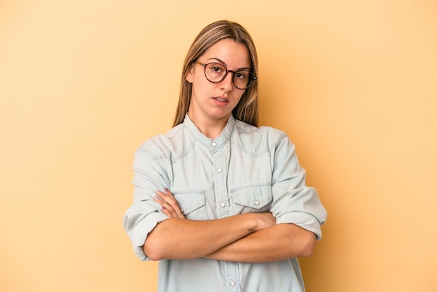 Jovem mulher caucasiana, isolada em um fundo amarelo, que está entediada, cansada e precisa de um dia de relaxamento.