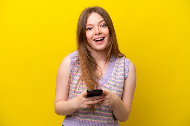 Jovem mulher caucasiana isolada em um fundo amarelo surpresa e enviando uma mensagem