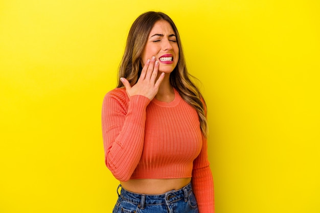 Jovem mulher caucasiana, isolada em um fundo amarelo, tendo uma forte dor nos dentes, dor molar.