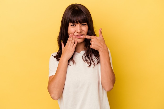 Jovem mulher caucasiana, isolada em um fundo amarelo, tendo uma forte dor nos dentes, dor molar.