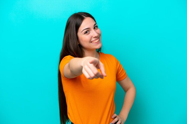 Foto jovem mulher caucasiana isolada em um fundo azul apontando para a frente com uma expressão feliz