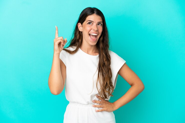 Foto jovem mulher caucasiana isolada em um fundo azul apontando para cima e surpresa