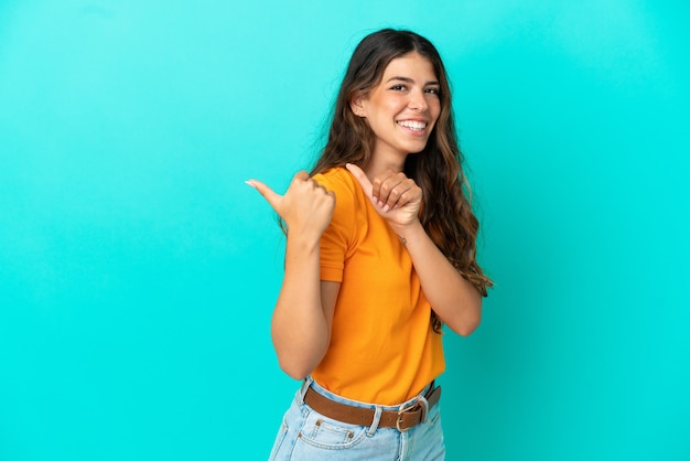 Jovem mulher caucasiana isolada em um fundo azul apontando para o lado para apresentar um produto