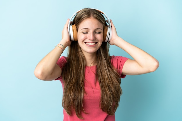 Jovem mulher caucasiana isolada em um fundo azul ouvindo música