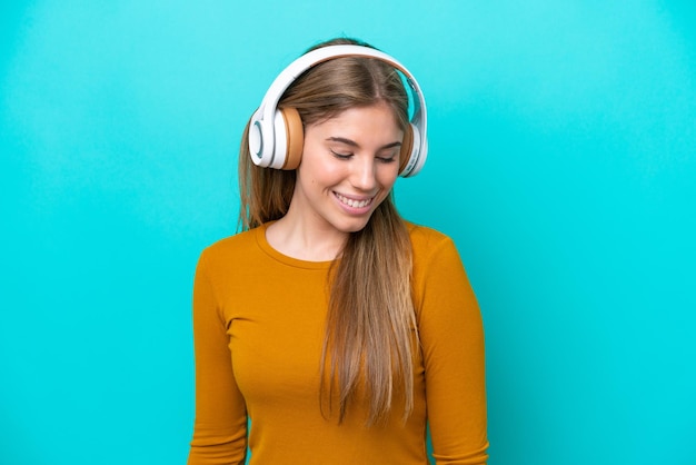 Jovem mulher caucasiana isolada em um fundo azul ouvindo música