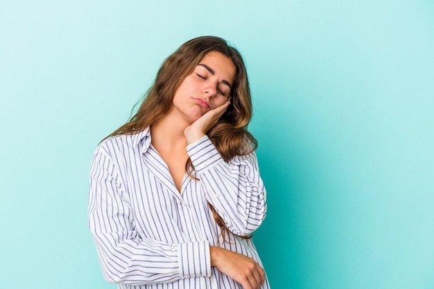 Jovem mulher caucasiana isolada em um fundo azul que está entediada, cansada e precisa de um dia de relaxamento.