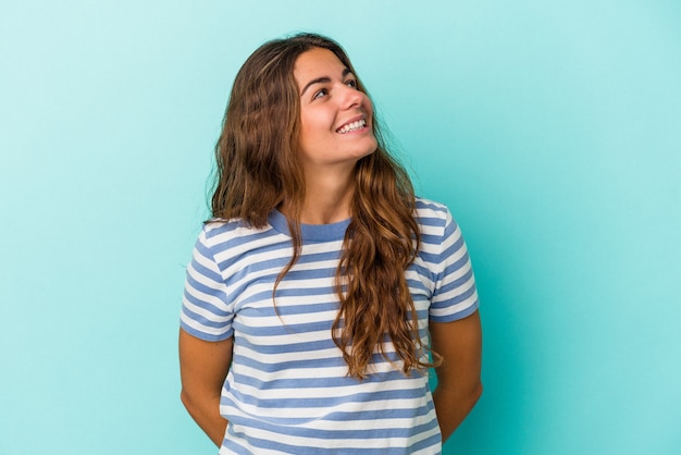 Jovem mulher caucasiana isolada em um fundo azul relaxada e feliz rindo, pescoço esticado, mostrando os dentes.