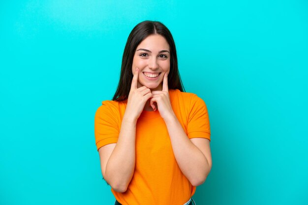 Jovem mulher caucasiana isolada em um fundo azul sorrindo com uma expressão feliz e agradável