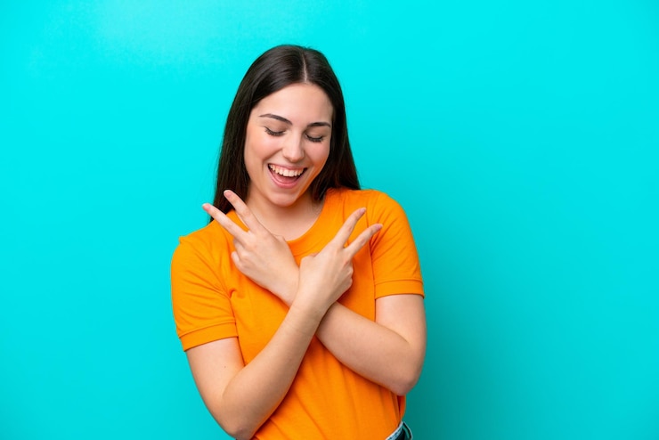 Foto jovem mulher caucasiana isolada em um fundo azul sorrindo e mostrando sinal de vitória