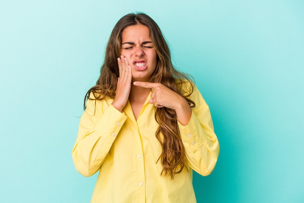 Jovem mulher caucasiana isolada em um fundo azul, tendo uma forte dor nos dentes, dor molar.