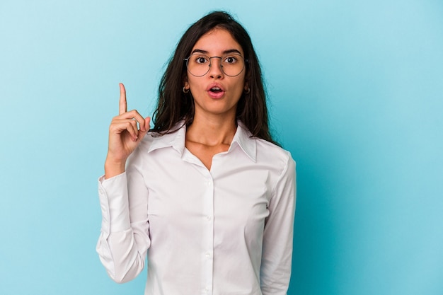 Jovem mulher caucasiana isolada em um fundo azul, tendo uma ideia, o conceito de inspiração.