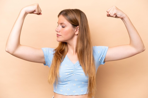 Jovem mulher caucasiana isolada em um fundo bege fazendo um gesto forte