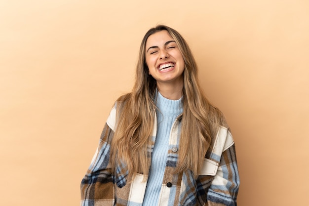 Jovem mulher caucasiana isolada em um fundo bege rindo