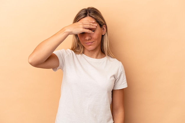 Jovem mulher caucasiana isolada em um fundo bege, tocando as têmporas e tendo dor de cabeça.