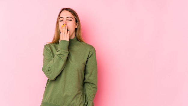 Jovem mulher caucasiana isolada em um fundo rosa bocejando, mostrando um gesto cansado, cobrindo a boca com a mão.