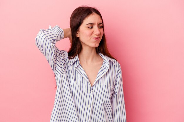 Jovem mulher caucasiana isolada em um fundo rosa cansada e com muito sono, mantendo a mão na cabeça.