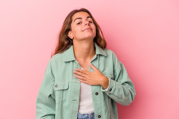 Jovem mulher caucasiana isolada em um fundo rosa, fazendo um juramento, colocando a mão no peito.