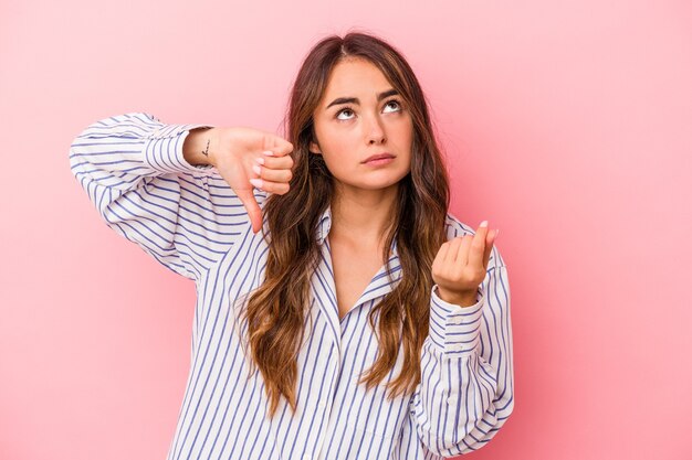 Jovem mulher caucasiana isolada em um fundo rosa, mostrando que ela não tem dinheiro.