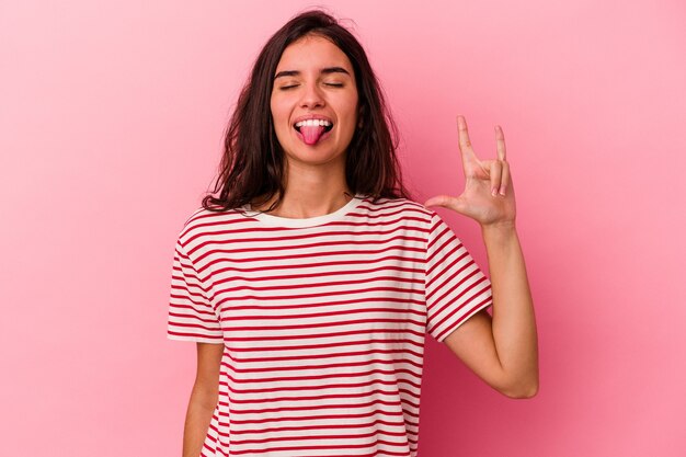 Jovem mulher caucasiana isolada em um fundo rosa mostrando um gesto de pedra com os dedos