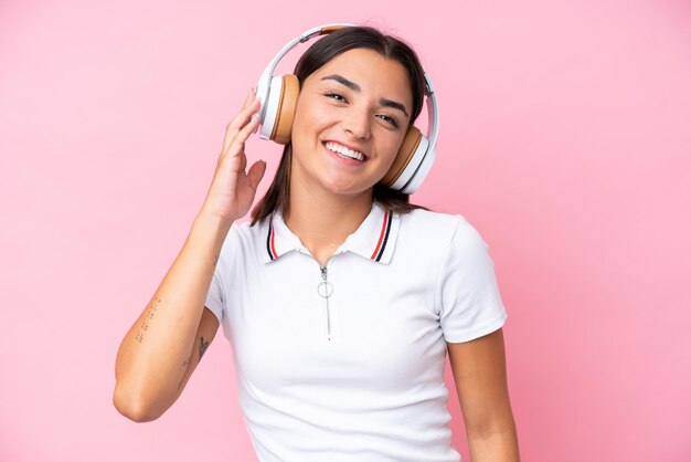 Jovem mulher caucasiana isolada em um fundo rosa ouvindo música