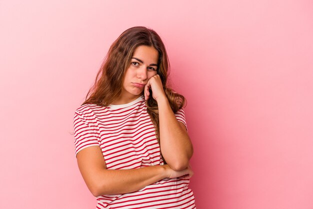 Jovem mulher caucasiana isolada em um fundo rosa que se sente triste e pensativa, olhando para o espaço da cópia.