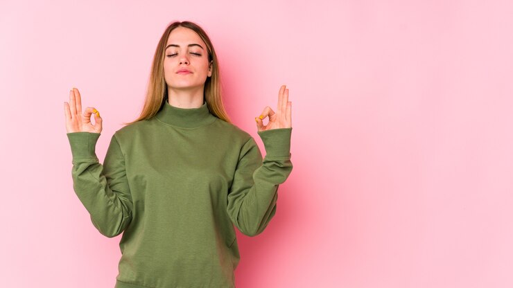 Foto jovem mulher caucasiana isolada em um fundo rosa relaxa após um árduo dia de trabalho, ela está realizando ioga.