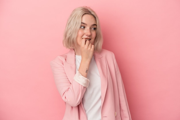 Jovem mulher caucasiana isolada em um fundo rosa relaxado pensando em algo olhando para um espaço de cópia.