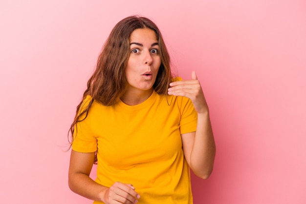 Jovem mulher caucasiana isolada em um fundo rosa, rindo de algo, cobrindo a boca com as mãos.