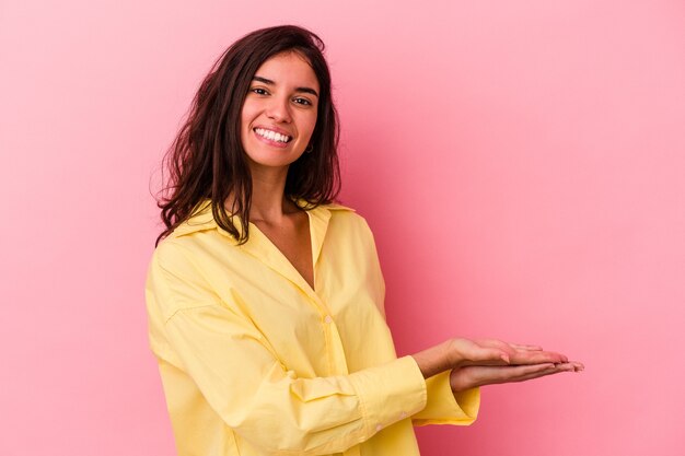 Foto jovem mulher caucasiana isolada em um fundo rosa, segurando um espaço de cópia na palma da mão.