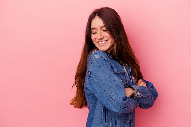 Jovem mulher caucasiana isolada em um fundo rosa, sorrindo confiante com os braços cruzados.