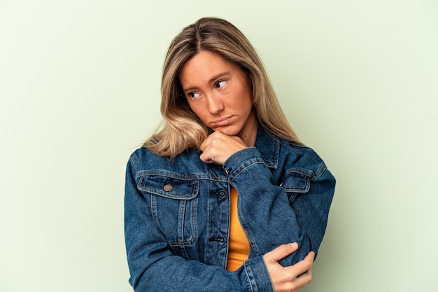 Jovem mulher caucasiana isolada em um fundo verde, cansada de uma tarefa repetitiva.