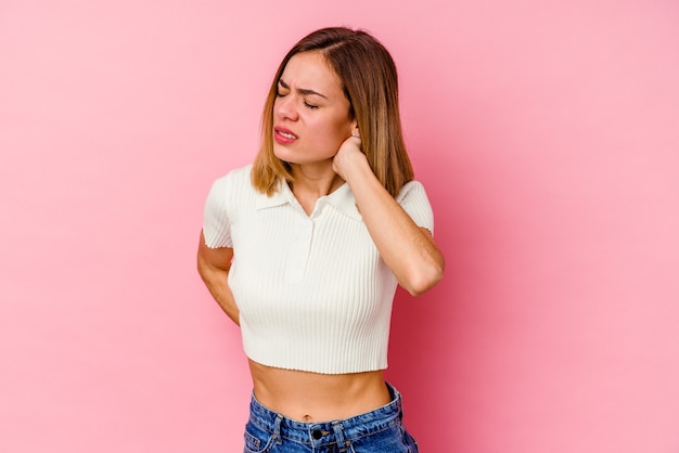 Jovem mulher caucasiana, isolada em uma parede rosa, tendo uma dor no pescoço devido ao estresse, massageando e tocando com a mão